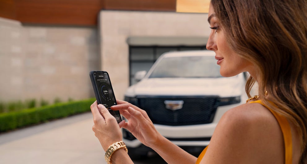 lady checking her mobile with a Cadillac vehicle background | Grand Island Cadillac in GRAND ISLAND NE